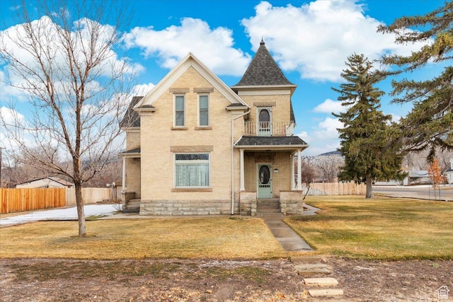 victorian home with a balcony and a front yard