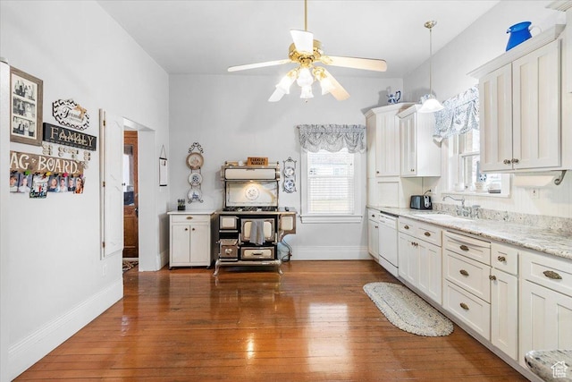 kitchen with light stone counters, white dishwasher, dark wood-type flooring, sink, and white cabinets