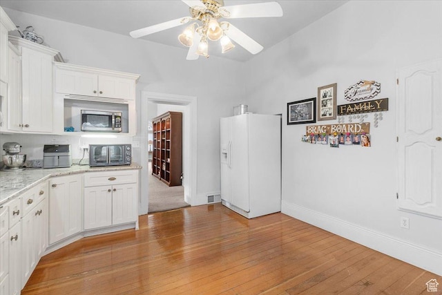 kitchen with ceiling fan, white fridge with ice dispenser, white cabinets, and light hardwood / wood-style flooring