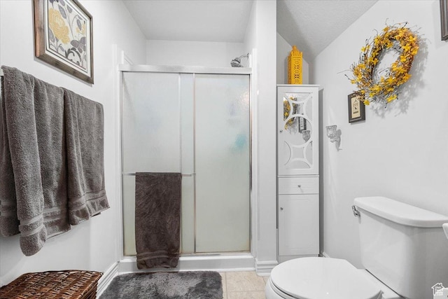bathroom with tile patterned flooring, a textured ceiling, toilet, and a shower with door