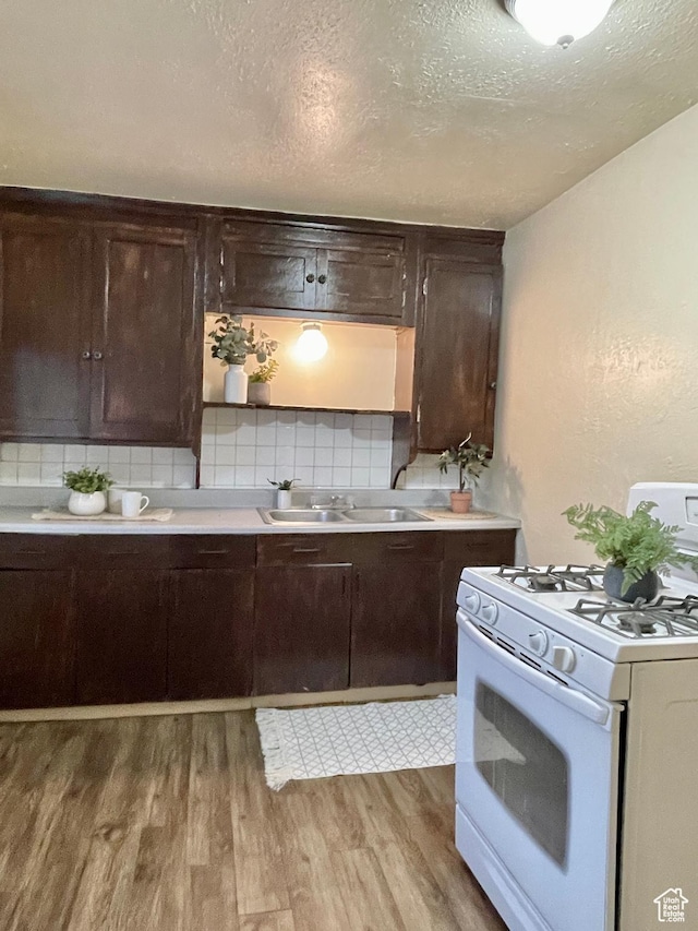 2433 Monroe Blvd, Ogden, UT 84401 - kitchen with a sink, dark brown cabinets, backsplash, light wood finished floors, and white gas range