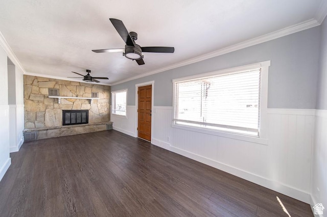 unfurnished living room featuring dark hardwood / wood-style floors, ceiling fan, a stone fireplace, and ornamental molding