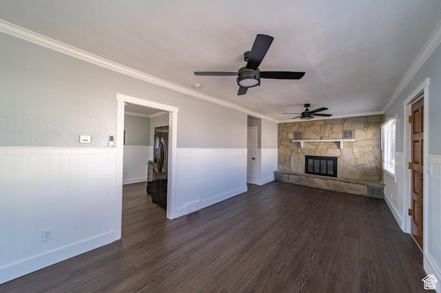 unfurnished living room with ceiling fan, dark hardwood / wood-style floors, a stone fireplace, and ornamental molding