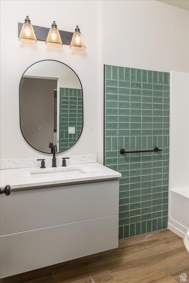 bathroom featuring a washtub, hardwood / wood-style floors, vanity, and toilet
