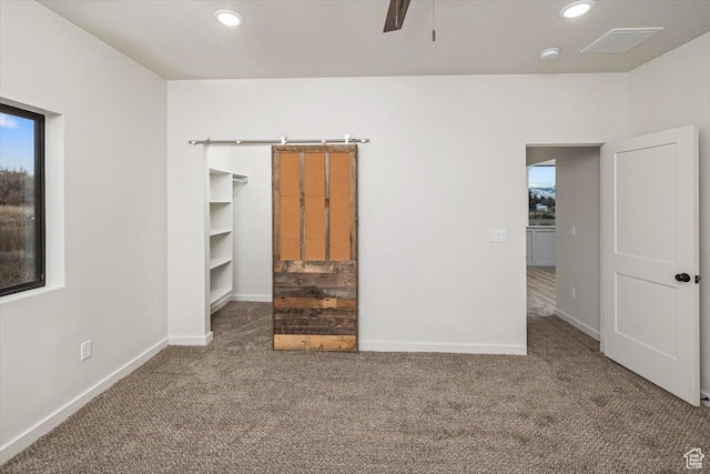 unfurnished bedroom featuring carpet, ceiling fan, a spacious closet, and a closet