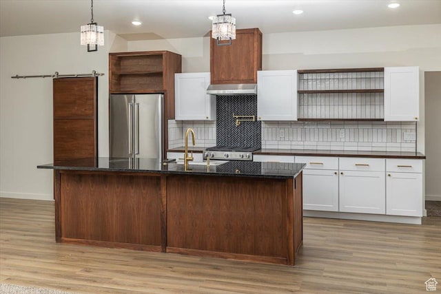 kitchen with a center island with sink, white cabinets, decorative light fixtures, and premium appliances