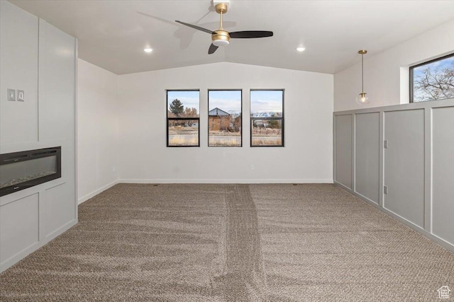 basement featuring light colored carpet, plenty of natural light, and ceiling fan