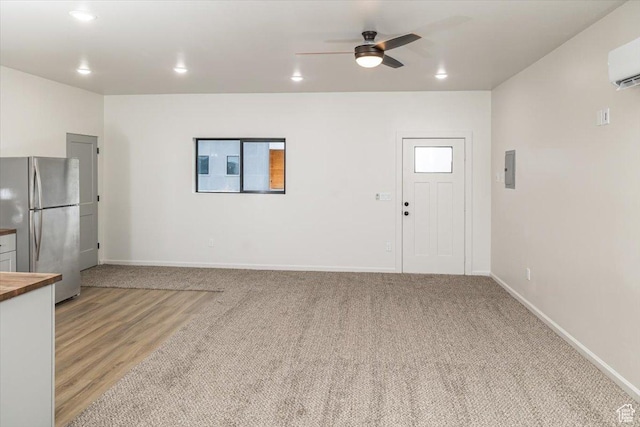 unfurnished living room featuring ceiling fan, light carpet, and a wall unit AC