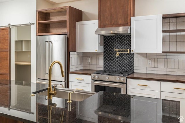 kitchen with white cabinetry, a barn door, ventilation hood, backsplash, and high end appliances