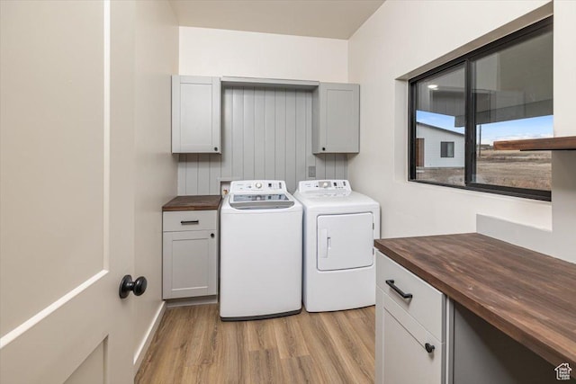 washroom with cabinets, washing machine and dryer, and light hardwood / wood-style flooring