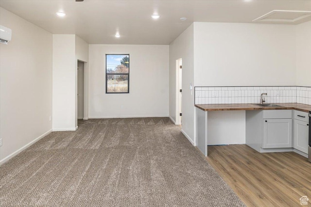 empty room with carpet, a wall unit AC, and sink