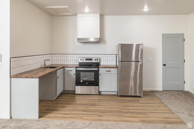 kitchen with wooden counters, sink, light wood-type flooring, appliances with stainless steel finishes, and tasteful backsplash