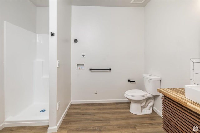 bathroom featuring walk in shower, vanity, wood-type flooring, and toilet