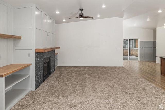 carpeted living room featuring ceiling fan and a fireplace