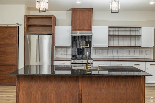 kitchen with high end appliances, backsplash, white cabinets, light wood-type flooring, and a kitchen island
