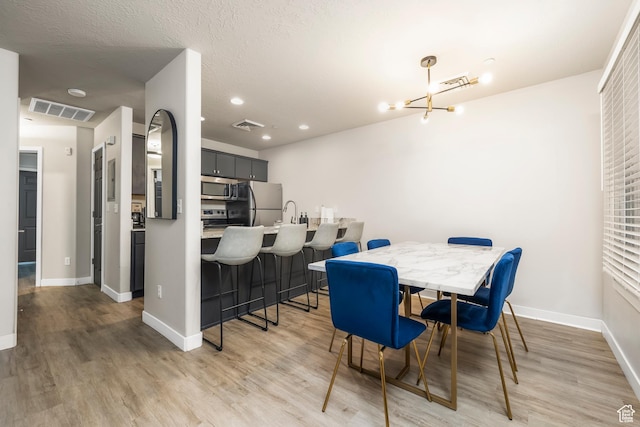 159 E 800 S Unit 208, Salt Lake City, UT 84111 - dining room featuring a textured ceiling, light wood-type flooring, and an inviting chandelier