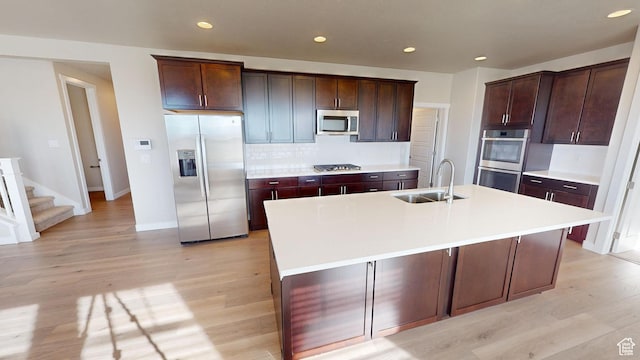 633 W Junegrass Ln, Stansbury Park, UT 84074 - kitchen with backsplash, dark brown cabinetry, stainless steel appliances, a kitchen island with sink, and sink