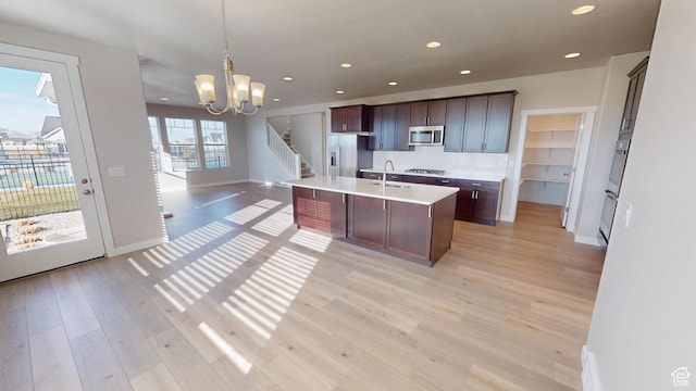633 W Junegrass Ln, Stansbury Park, UT 84074 - kitchen featuring light hardwood / wood-style flooring, a chandelier, pendant lighting, a center island with sink, and appliances with stainless steel finishes