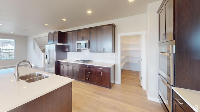 633 W Junegrass Ln, Stansbury Park, UT 84074 - kitchen featuring sink, stainless steel appliances, backsplash, dark brown cabinets, and light wood-type flooring