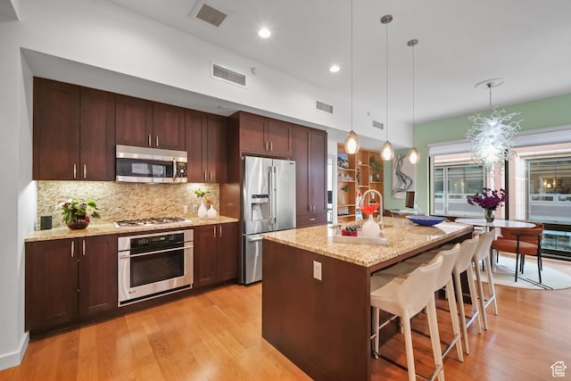 55 W S Temple Unit 204, Salt Lake City, UT 84101 - kitchen with visible vents, backsplash, light wood-type flooring, and appliances with stainless steel finishes