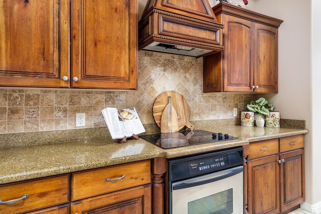 2371 E 2830 S, St George, UT 84790 - kitchen featuring light stone countertops, stainless steel oven, black electric cooktop, decorative backsplash, and custom exhaust hood