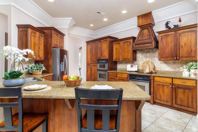 kitchen with sink, stainless steel appliances, a kitchen breakfast bar, backsplash, and light tile patterned floors