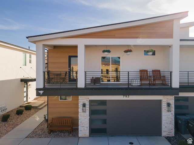 rear view of house featuring a balcony and a garage