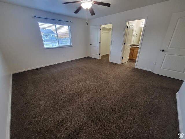 3318 E Quarter Mile Dr, Eagle Mountain, UT 84005 - unfurnished bedroom with baseboards, ceiling fan, ensuite bath, a spacious closet, and dark colored carpet