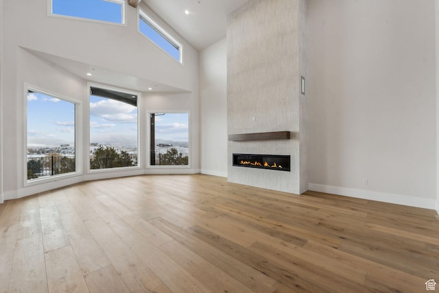 3097 E Corral Peak Cir Unit 145, Heber City, UT 84032 - unfurnished living room featuring baseboards, a high ceiling, a large fireplace, and hardwood / wood-style floors