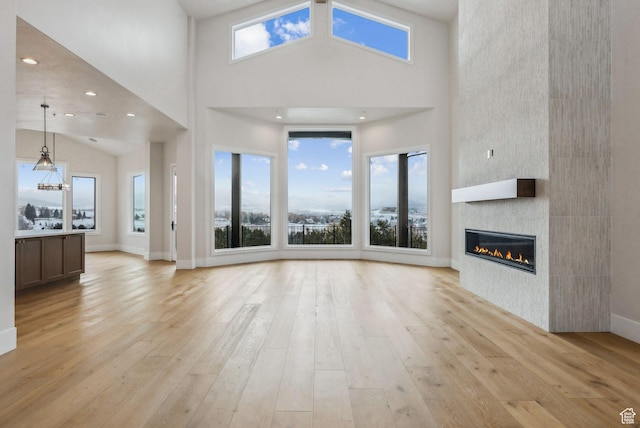 3097 E Corral Peak Cir Unit 145, Heber City, UT 84032 - unfurnished living room featuring light wood finished floors, a high ceiling, a large fireplace, and baseboards