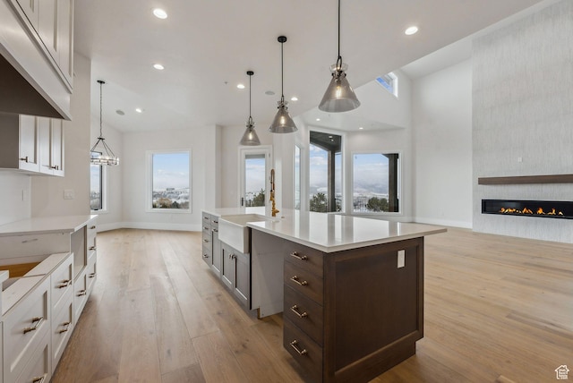 3097 E Corral Peak Cir Unit 145, Heber City, UT 84032 - kitchen featuring light wood-type flooring, dark brown cabinets, a large fireplace, light countertops, and a sink