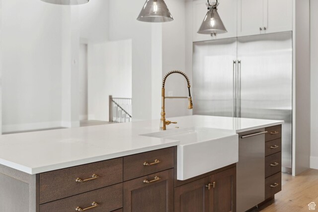 3097 E Corral Peak Cir Unit 145, Heber City, UT 84032 - kitchen featuring decorative light fixtures, a sink, light countertops, dark brown cabinets, and light wood finished floors