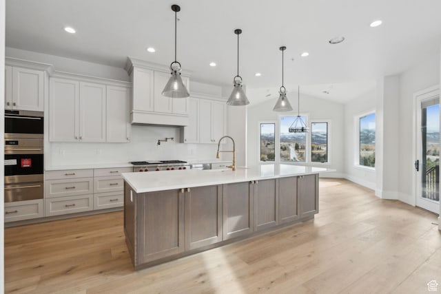 3097 E Corral Peak Cir Unit 145, Heber City, UT 84032 - kitchen featuring an island with sink, light wood-type flooring, a warming drawer, light countertops, and a sink