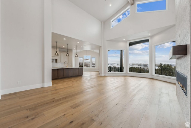 3097 E Corral Peak Cir Unit 145, Heber City, UT 84032 - unfurnished living room featuring light wood-type flooring, baseboards, a large fireplace, and a wealth of natural light