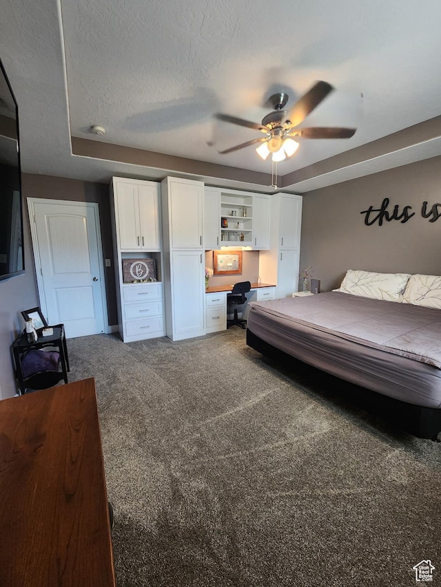 bedroom with ceiling fan, carpet, built in desk, and a textured ceiling