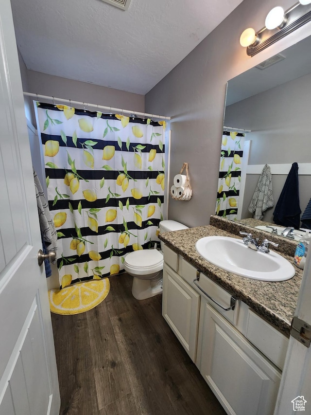 bathroom featuring a textured ceiling, vanity, hardwood / wood-style flooring, and toilet