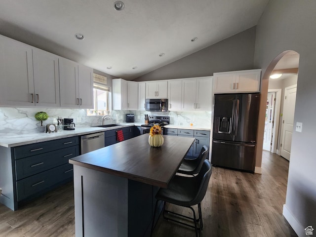 kitchen featuring a kitchen island, white cabinetry, backsplash, and appliances with stainless steel finishes