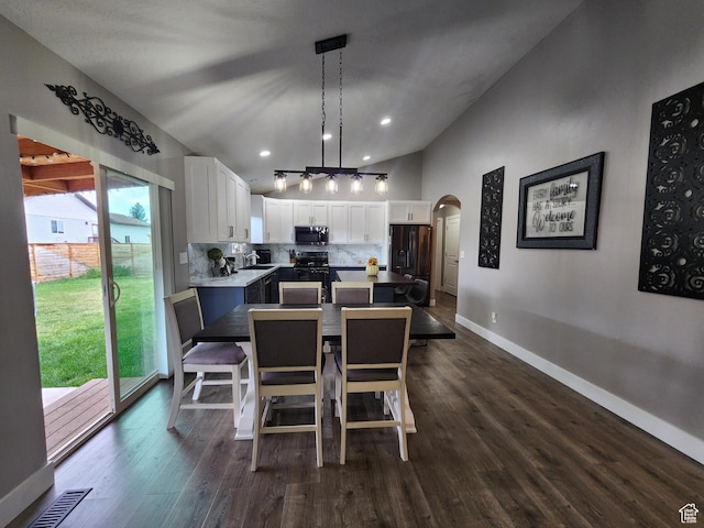dining space with sink, dark wood-type flooring, and a high ceiling