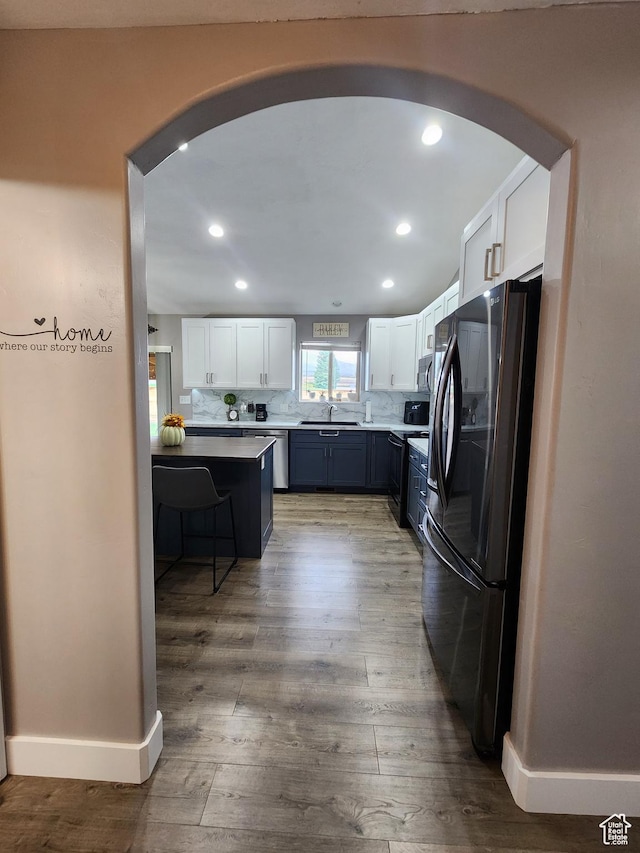 kitchen with white cabinetry, sink, dark wood-type flooring, refrigerator, and decorative backsplash