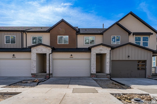 view of property featuring stucco siding, a garage, driveway, and stone siding