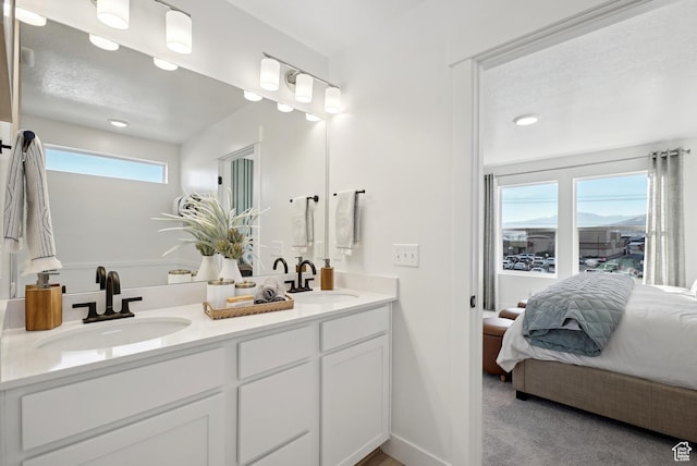 ensuite bathroom with double vanity, ensuite bath, and a sink