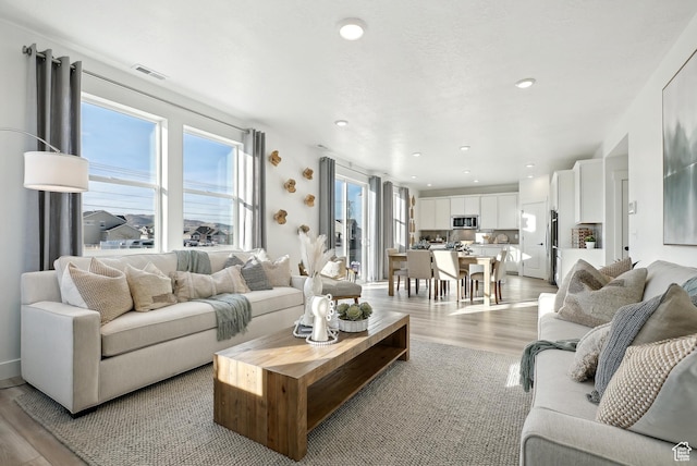 living area featuring visible vents, light wood-style flooring, and recessed lighting
