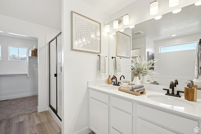 bathroom with a stall shower, wood finished floors, a sink, and visible vents