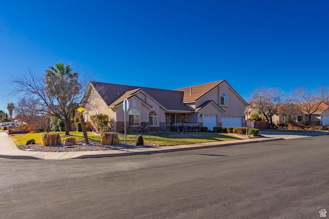 view of front facade with stucco siding, a front lawn, driveway, a garage, and a tiled roof
