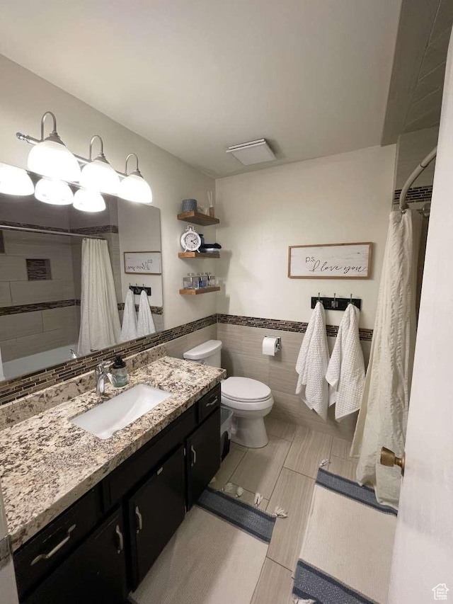bathroom featuring a shower with shower curtain, vanity, toilet, and tile walls