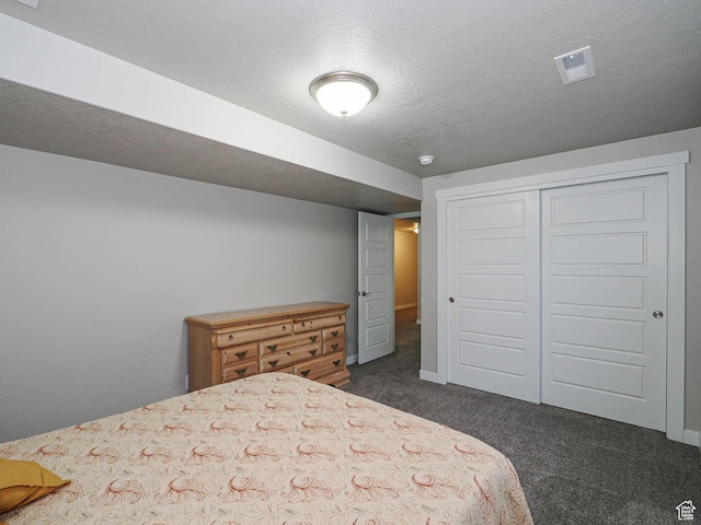 bedroom with dark colored carpet, visible vents, a closet, and baseboards