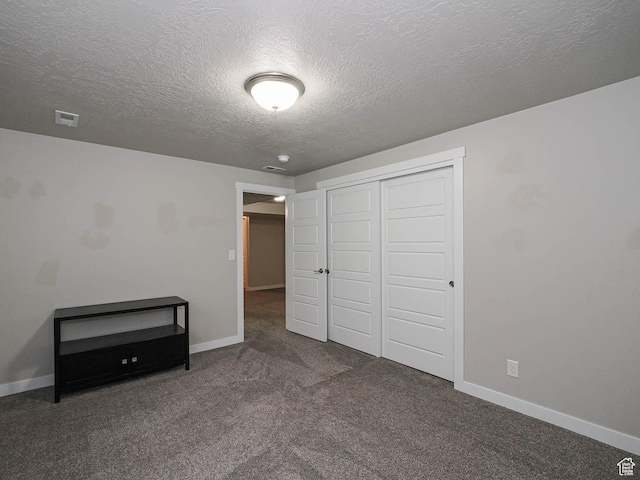 unfurnished bedroom with a textured ceiling, a closet, visible vents, carpet flooring, and baseboards
