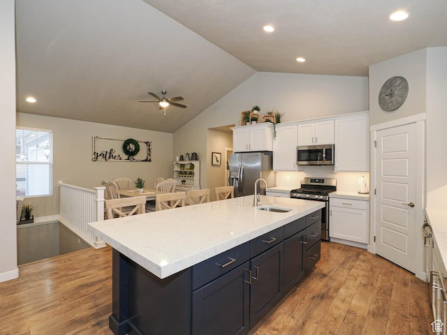 kitchen with a sink, white cabinetry, vaulted ceiling, stainless steel appliances, and light wood-style flooring