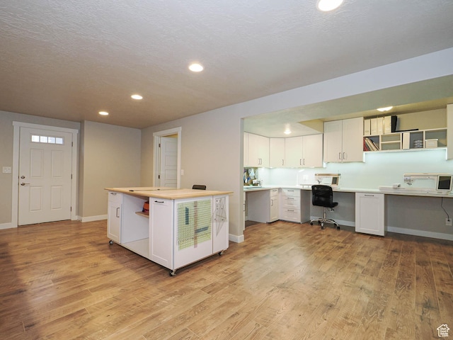 kitchen featuring open shelves, white cabinets, light countertops, built in study area, and light wood finished floors