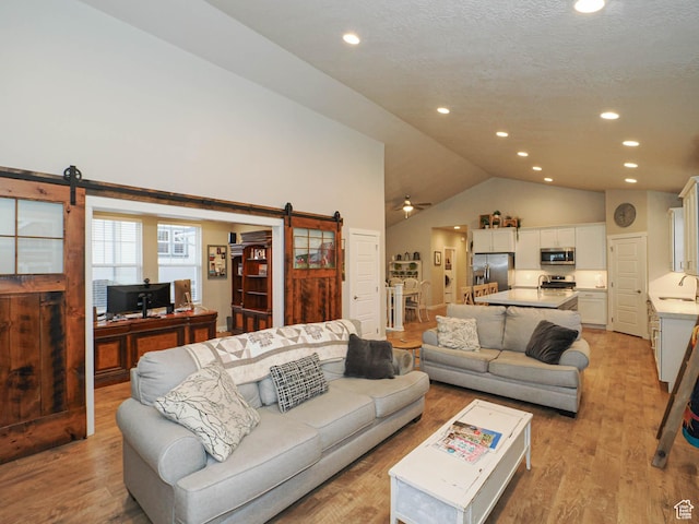 living area featuring recessed lighting, a barn door, light wood-type flooring, and lofted ceiling